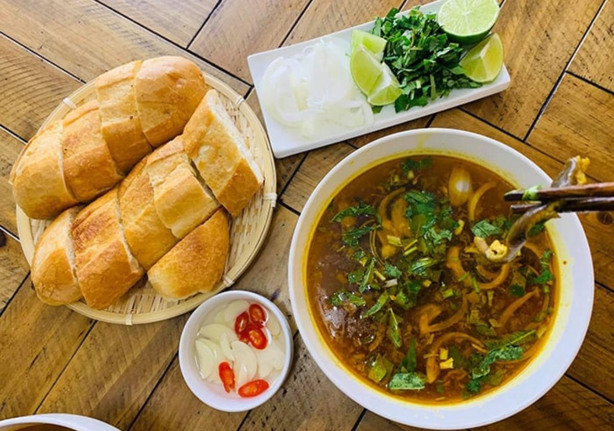 A bowl of soup next to bread and vegetables

Description automatically generated