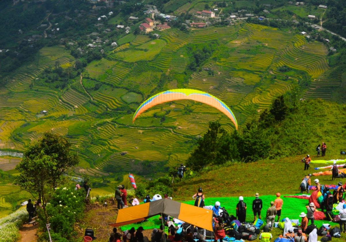 A group of people flying in the sky over a green field with Chocolate Hills in the background

Description automatically generated