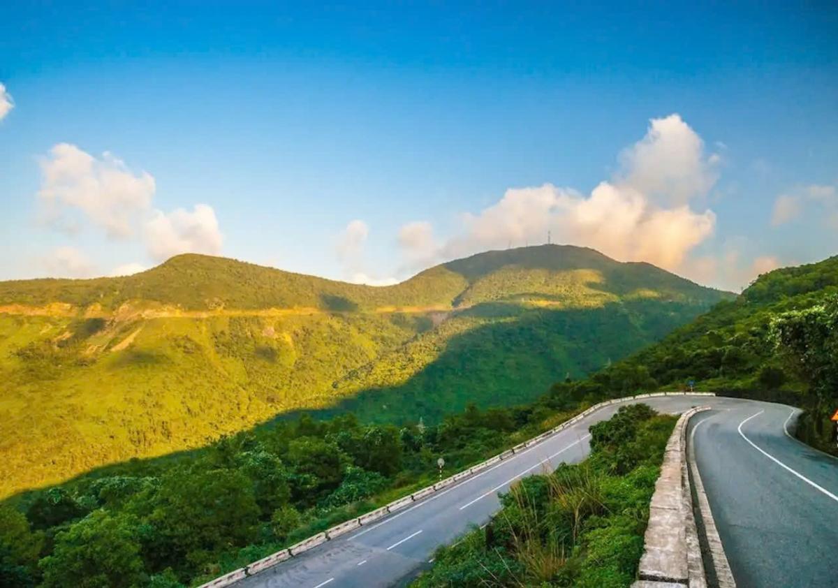 A road with trees and mountains in the backgroundDescription automatically generated