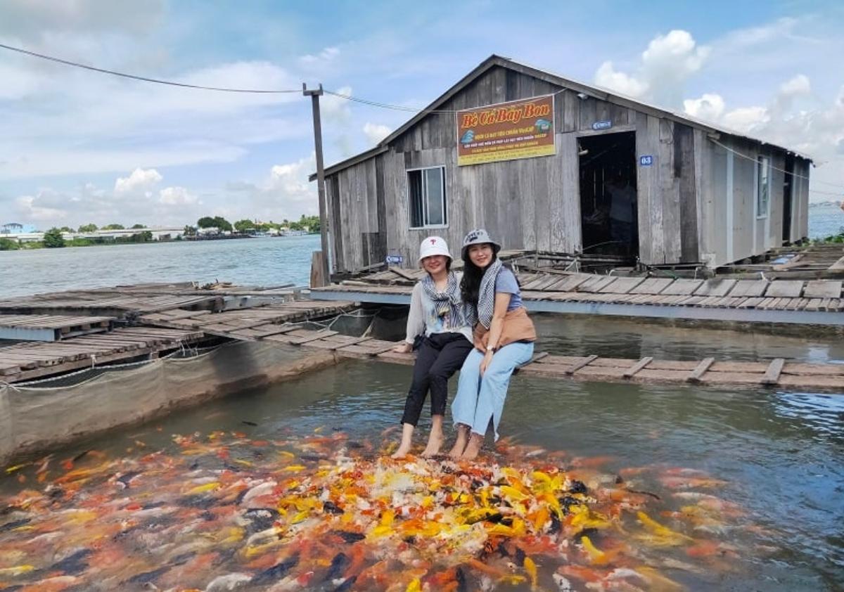 Two women sitting on a bench in a pond with fishDescription automatically generated