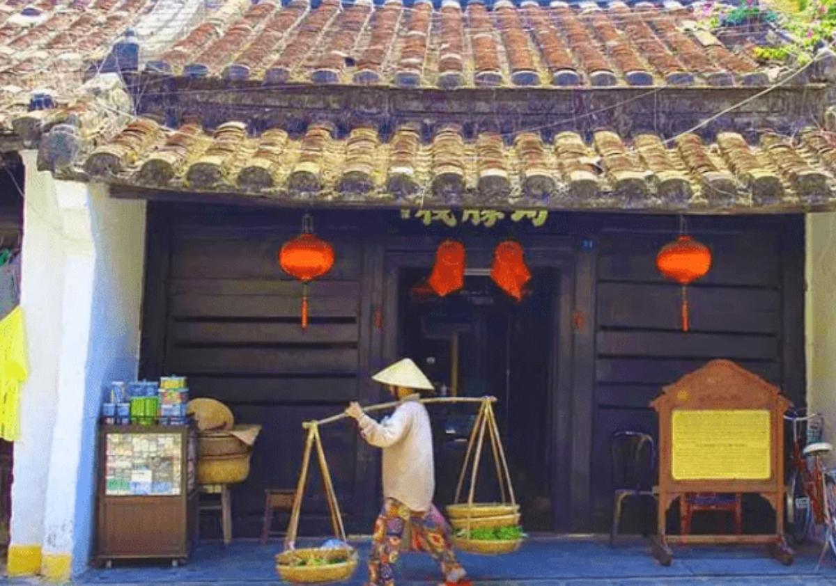 A person carrying baskets in front of a building

Description automatically generated